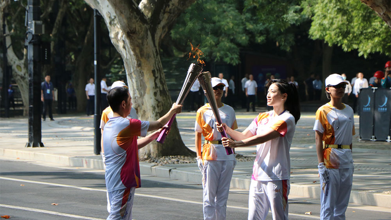 Hai thành viên rước đuốc trao truyền lửa thiêng ASIAD 19. (Ảnh: people.com.cn)