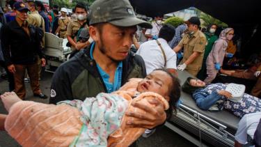Một đứa trẻ bị thương được cha bế đến nơi chữa trị tại Cianjur, Indonesia, ngày 21/11.