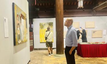 Một du khách nước ngoài chăm chú trước một tác phẩm trưng bày tại triển lãm.