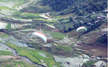 Du khách trải nghiệm bay dù lượn trên ruộng bậc thang huyện Mù Cang Chải, tỉnh Yên Bái trong mùa nước đổ. (Ảnh: ĐỨC TƯỞNG)